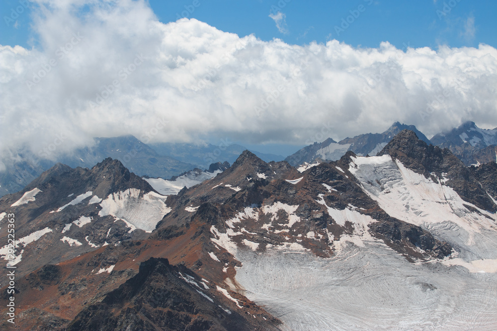 Caucasus mountains near Elbrus volcano with glaciers, clouds and peaks.