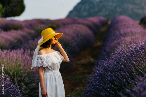 a young beautiful woman with yellow hat at lavender field, she is feeling nature 