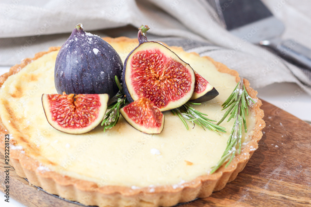 delicious round french classic homemade shortcake pastry dough vanilla custard tart cake decorated with figs and rosemary on wooden plate near with retro fork on grey table cloth. Insta food style delicious round french classic homemade shortcake pastry dough vanilla custard tart cake decorated with figs and rosemary on wooden plate near with retro fork on grey table cloth. Insta food style
