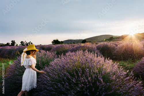 a young beautiful woman with yellow hat at lavender field, she is feeling nature 
