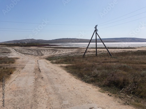Gloomy Crimean landscape. Empty road, electrical transmission line and peloid salt lake in background