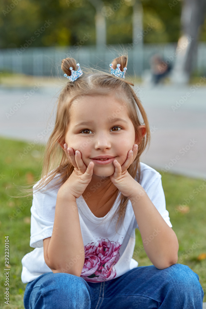 Beautiful little girl outdoors in a park. Lifestyle happy portrait of a little girl outdoors in a meadow. Beautiful little girl outdoors in a park. Lifestyle happy portrait of a little girl outdoors in a meadow.