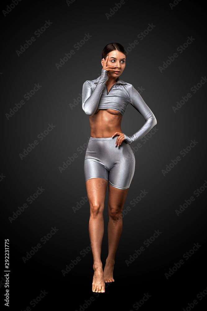 sexy brunette girl with a slim figure in leggings posing in studio on a  black background Stock Photo | Adobe Stock