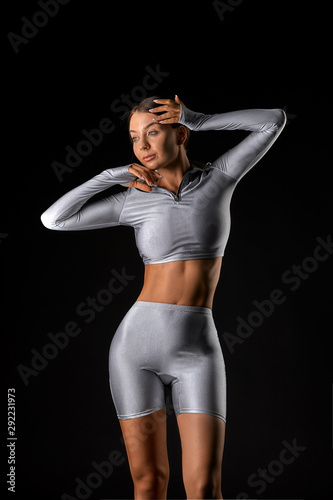 sexy brunette girl with a slim figure in leggings posing in studio on a  black background Stock Photo | Adobe Stock