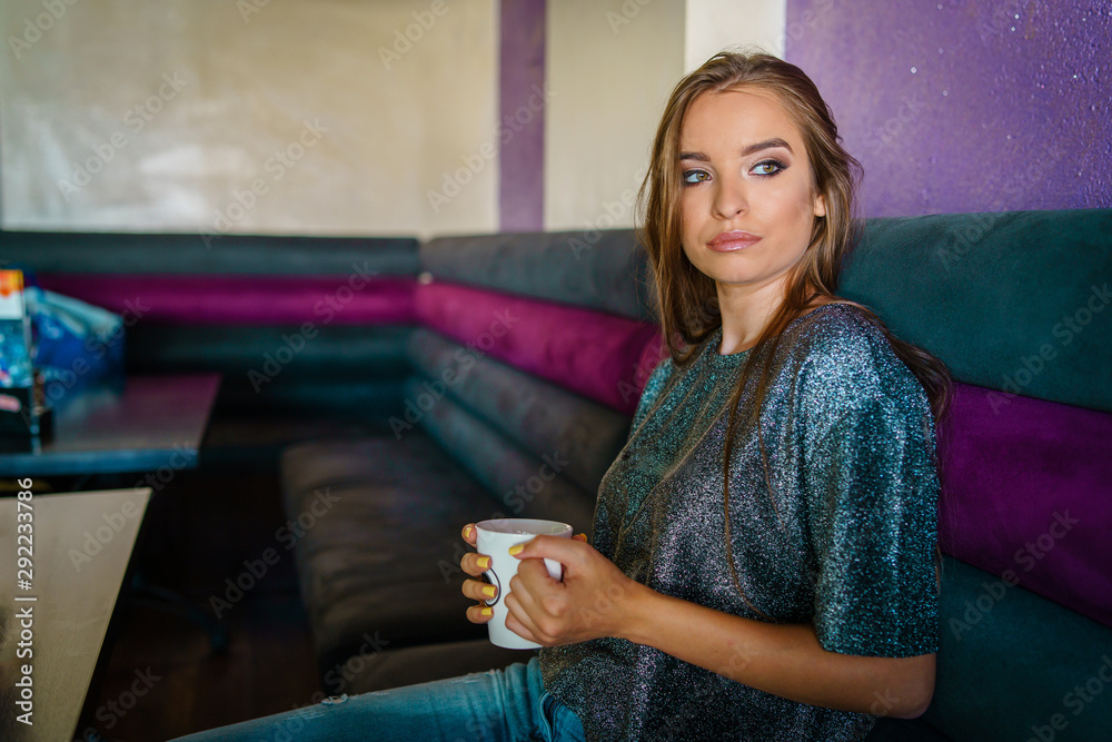Portrait of young beautiful woman girl sitting alone at cafe having a cup of coffee or tea