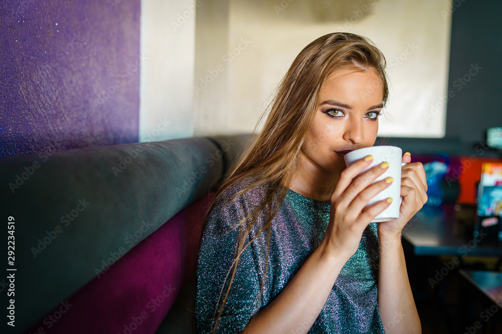 Portrait of young beautiful woman girl sitting alone at cafe having a cup of coffee or tea Portrait of young beautiful woman girl sitting alone at cafe having a cup of coffee or tea