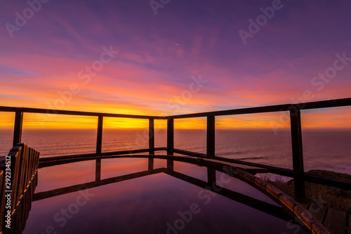 An amazing an idyllic view a wooden hot tub waiting us for some relaxation time during sunset and twilight before an awe night sky with a small crescent moon. A leisure activity at Chilean coastline