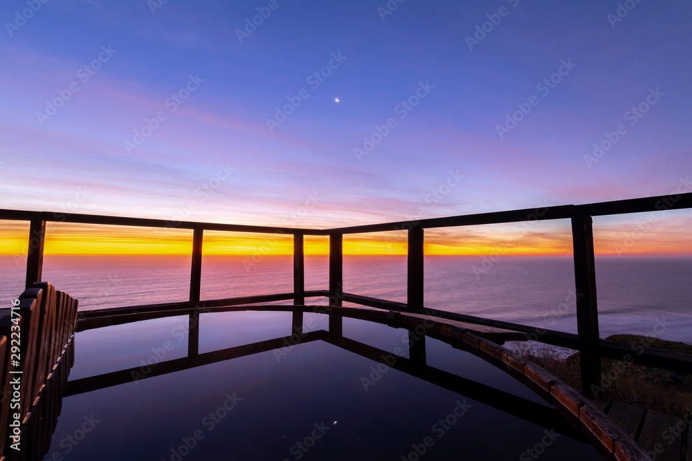 An amazing an idyllic view a wooden hot tub waiting us for some relaxation time during sunset and twilight before an awe night sky with a small crescent moon. A leisure activity at Chilean coastline An amazing an idyllic view a wooden hot tub waiting us for some relaxation time during sunset and twilight before an awe night sky with a small crescent moon. A leisure activity at Chilean coastline
