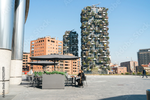 man sitting next to his guitar with a backgroung of green skyscreaper photo