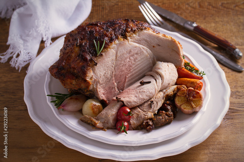 Baked ham on white plate, table with Christmas decorations. Dish for Christmas Eve. Winter season holidays food