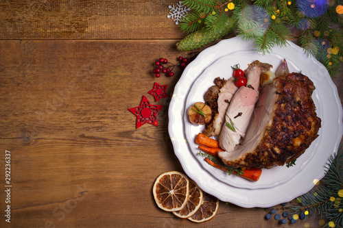 Baked ham on white plate, table with Christmas decorations. Dish for Christmas Eve. Winter season holidays food, room for text