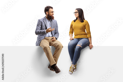 Bearded man talking to a young female seated on a banner photo