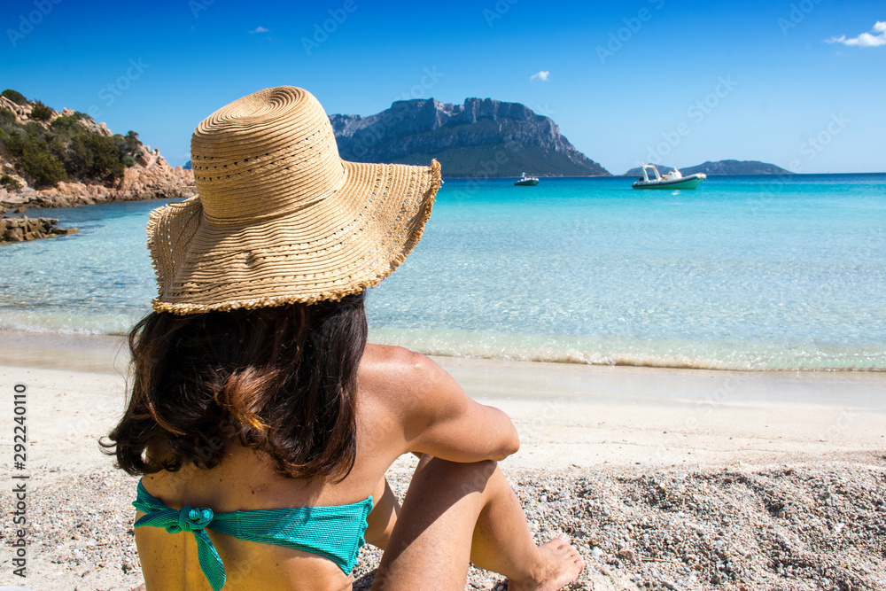 Woman sitting on the doctor's beach in Olbia, in a moment of relaxation, enjoying the view of the crystal clear sea on the north-eastern coast of Sardinia - Olbia / Tempio