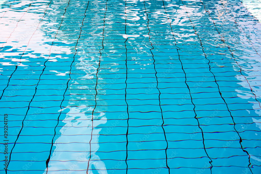 Pure blue water in the pool. Water background. Swimming pool bottom caustics ripple and flow with waves background. Water in swimming pool rippled water detail background. Side view.
