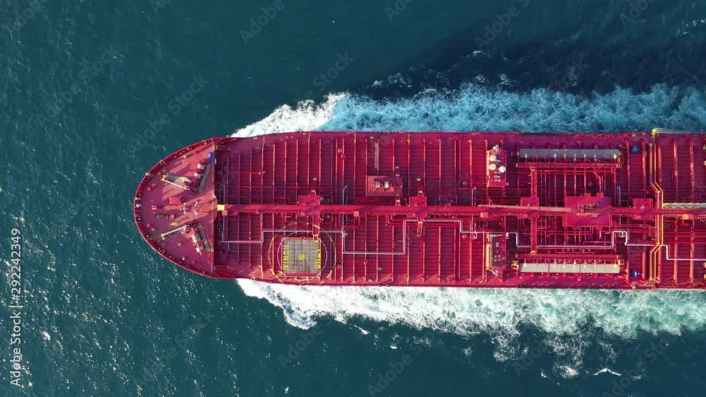 Aerial top down tracking video of industrial oil and fuel tanker cruising open ocean sea