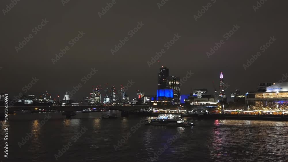 A night view of boats crossing Thames river in London city. A night view of boats crossing Thames river in London city.