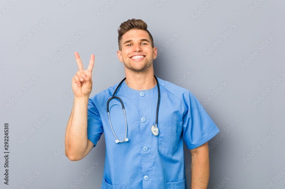 Young nurse man showing number two with fingers. Young nurse man showing number two with fingers.