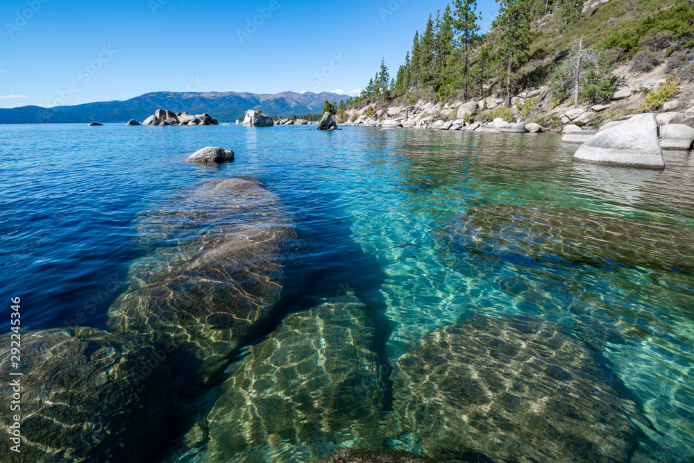 USA, Nevada, Washoe County, Lake Tahoe. Granite boulders under the clear blue to emerald waters along the eastern shore. - obrazy, fototapety, plakaty 