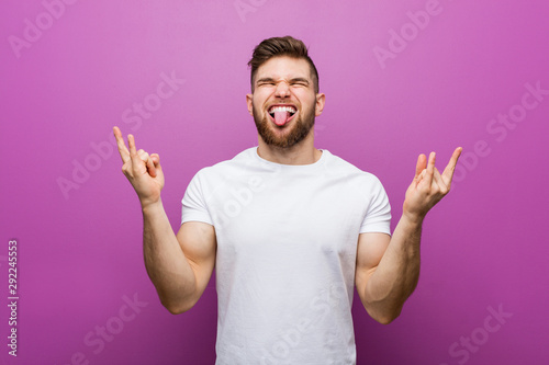 Young handsome caucasian man showing rock gesture with fingers