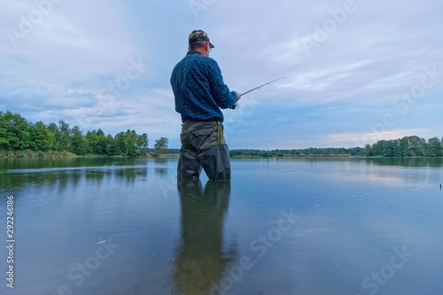 angler standing in the lake during cloudy day