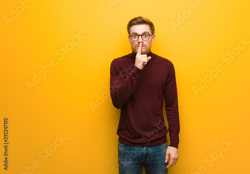 Young smart man keeping a secret or asking for silence