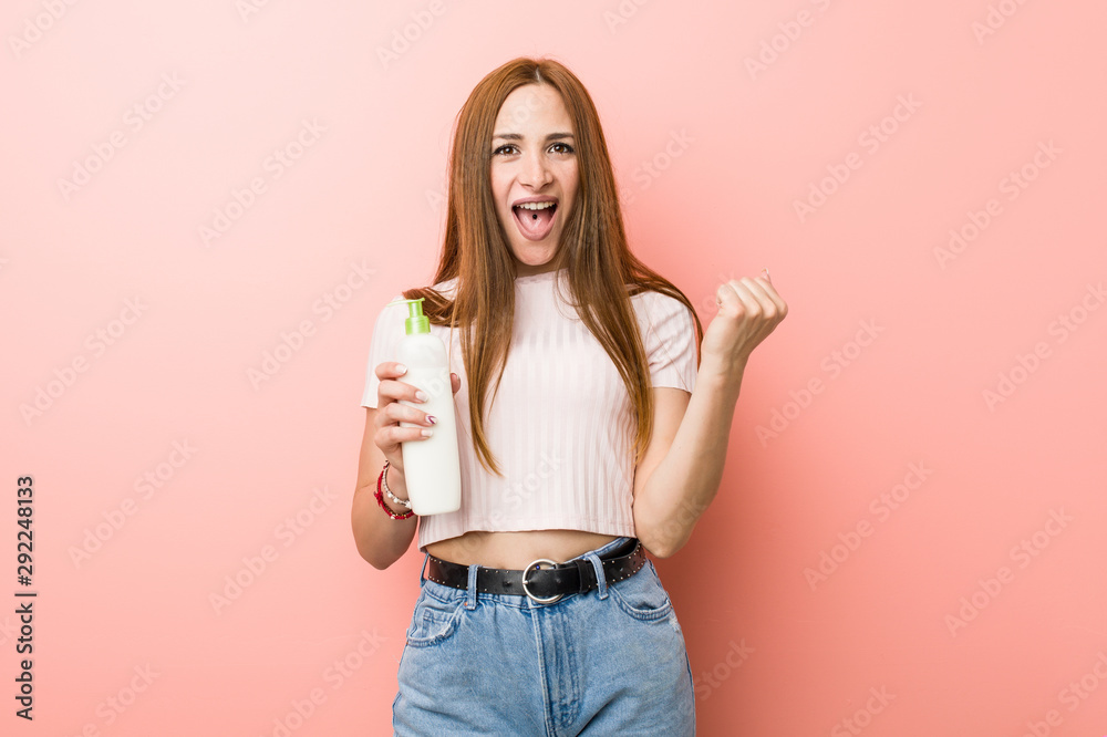 Young caucasian woman holding a cream bottle cheering carefree and excited. Victory concept. Young caucasian woman holding a cream bottle cheering carefree and excited. Victory concept.