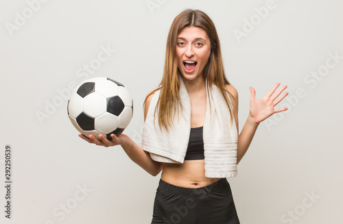 Young fitness russian woman celebrating a victory or success. Holding a soccer ball.