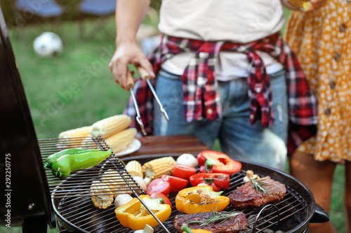 Man cooking food on barbecue grill outdoors, closeup