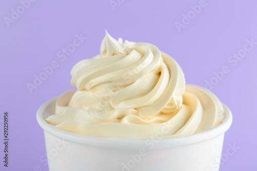 Cup with tasty frozen yogurt on violet background, closeup