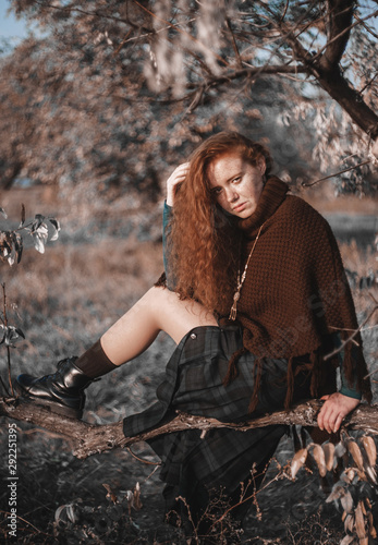 Redhead woman in poncho posing outdoors.