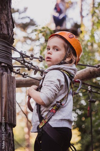 Little cute girl climbing in high rope course enjoying the adventure