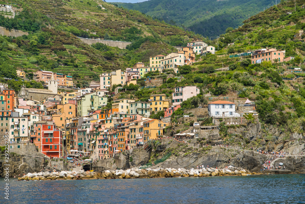 Riomaggiore, Cinque Terre, Italy - August 17, 2019: Village by the sea bay, colorful houses on the rocky coast. The protected area of ​​the mountains. A popular resort in Europe