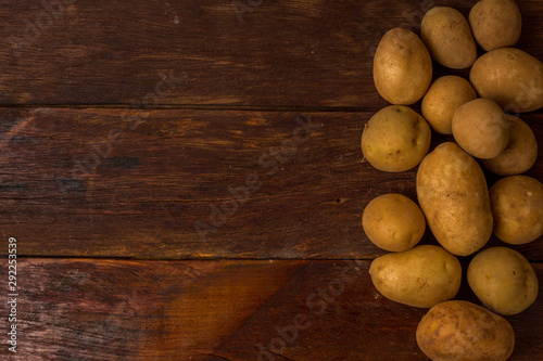 Fresh and raw potatoes stacked on wooden table, copy space and text. Rustic Style..