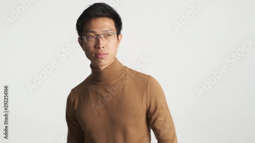 Young handsome stylish asian man in eyeglasses cool dancing on camera isolated. Dancing moves improvisation