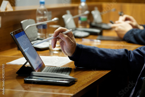 Men in suits during a business meeting. One of them - an official, businessman or deputy uses the touch screen of a tablet computer. Close-up photo