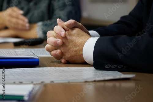 Hands of the boss during a meeting and adjudication. Clenched fingers. Teamwork photo