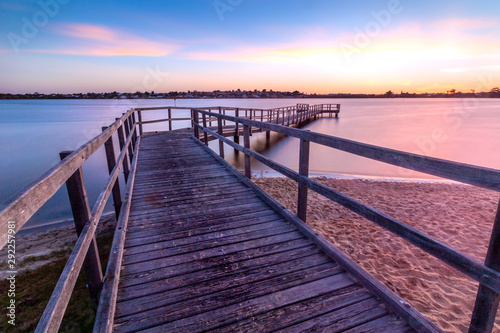 Long exposure photo of a pier on sunset in the evening with a colourful sky and clouds