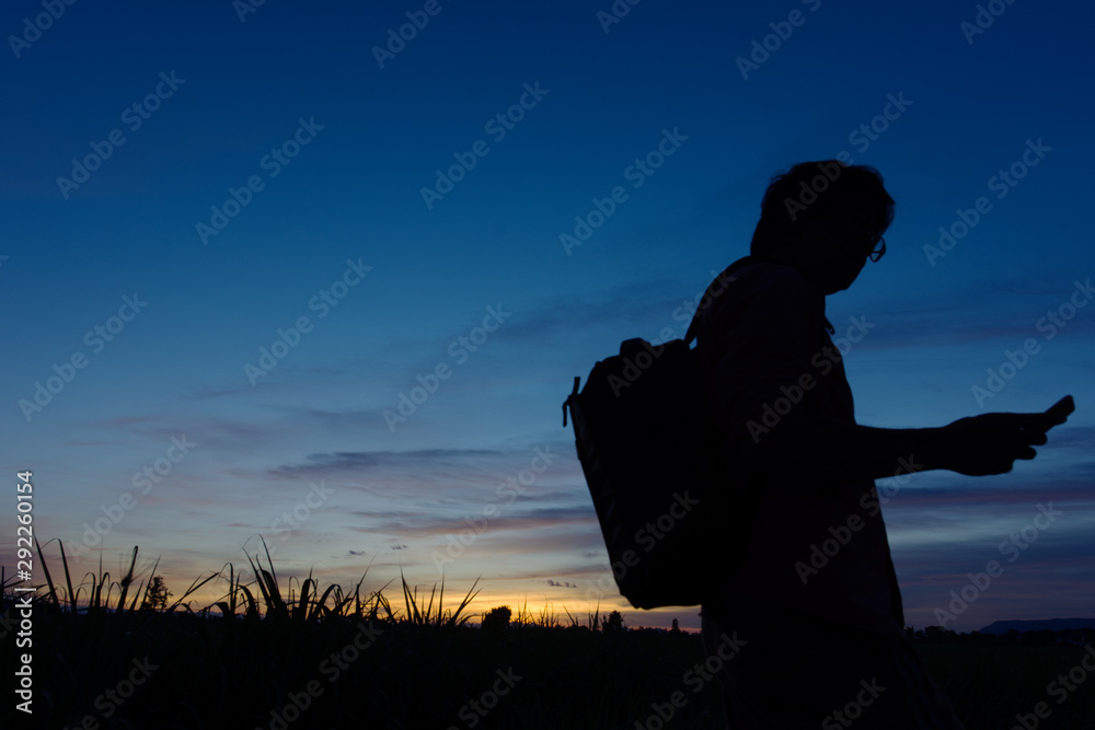 a man hold mobile phone in hand searching for signal when sunset moment.