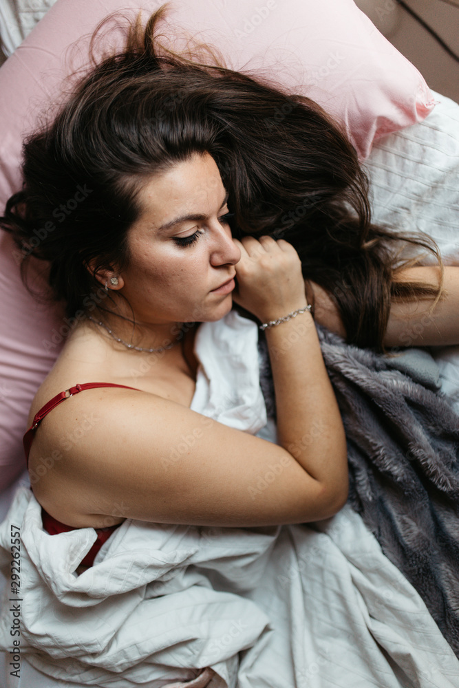 Pensive and attractive sad woman lying on the bed. Thinking about problems. Feeling worried, hurt, heartbroken lonely Pensive and attractive sad woman lying on the bed. Thinking about problems. Feeling worried, hurt, heartbroken lonely