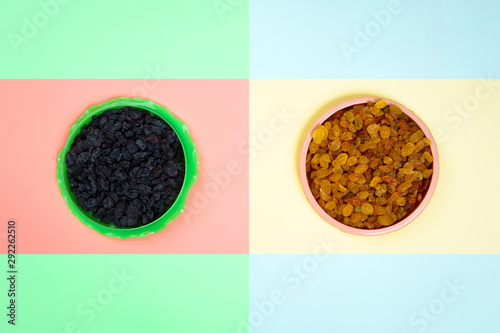 Minimalistic flat bark with plastic plates with yellow and black raisins on a yellow-pink isolated background. The concept of choosing food, right or bad. the concept of tasty and proper food photo