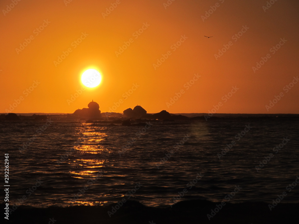 A beautiful sunset with the sun approaching the horizon at the sea seen from the beach of Algarrobo, Chili