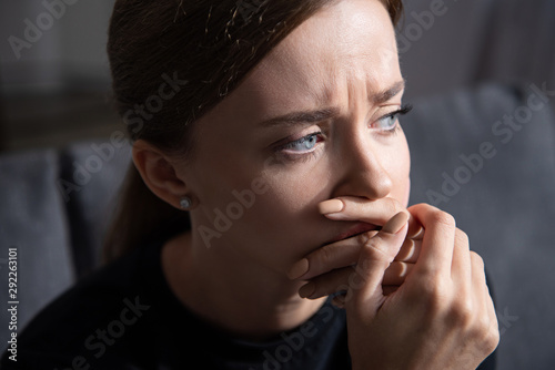 upset young woman covering mouth with hand and looking away