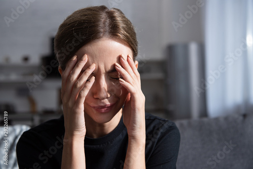 beautiful upset young woman crying and touching face with hands at home