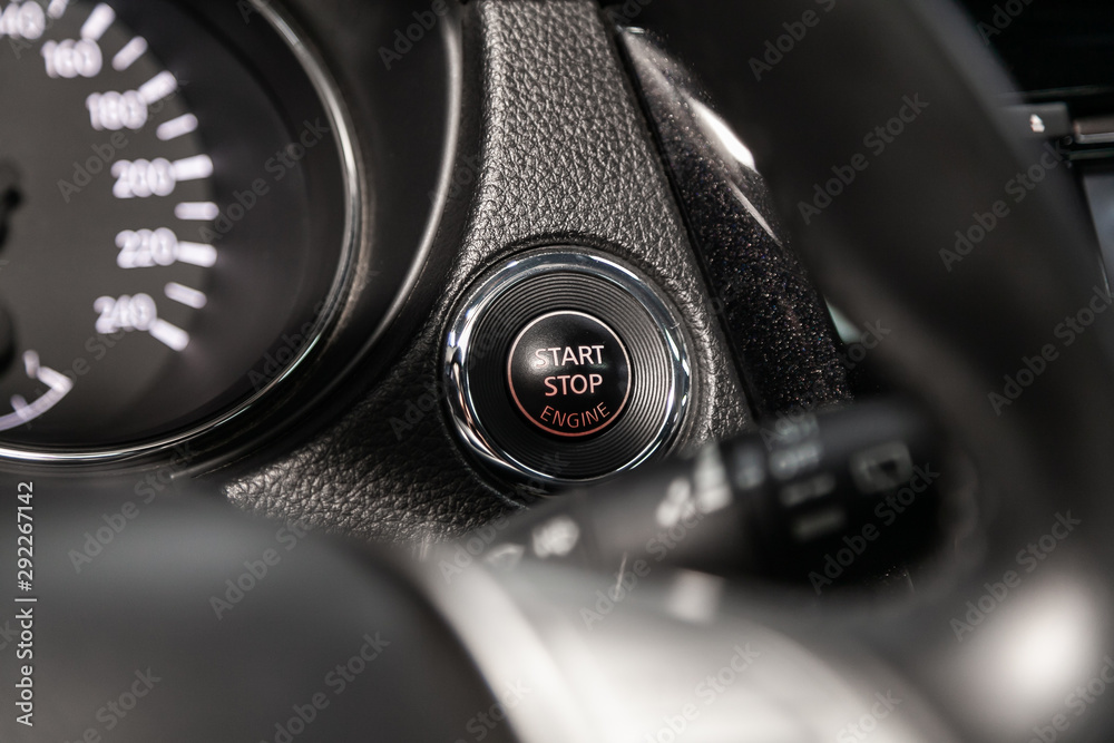 Car engine push start stop button ignition remote starter. Car dashboard:  black engine start stop button, car interior details. Soft focus