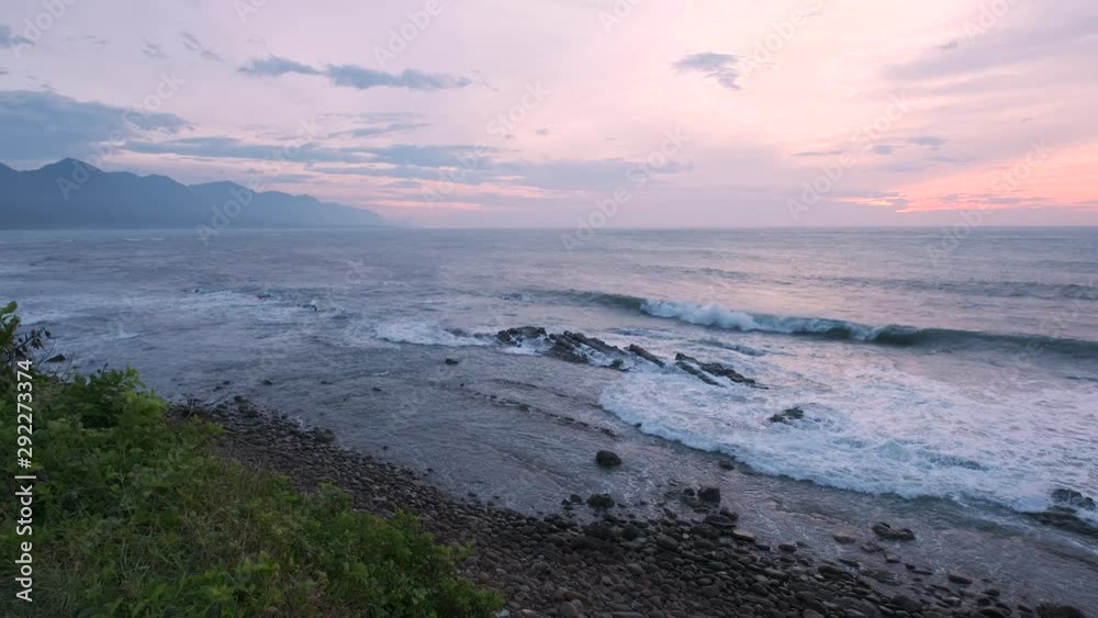 Sun Rises Over Ocean As Waves Crash On Beach With Mountains In Background - Taiwan, Taidong Sun Rises Over Ocean As Waves Crash On Beach With Mountains In Background - Taiwan, Taidong
