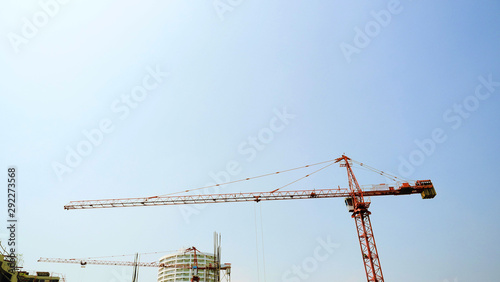 Red tower crane in the building construction area with blue sky in background, Machinery and large working equipment