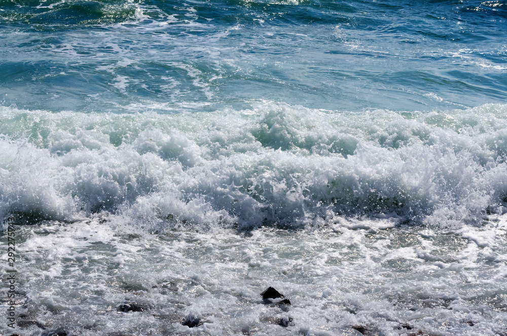 Fototapeta premium The sea waves rolling on the stony coast, a close up