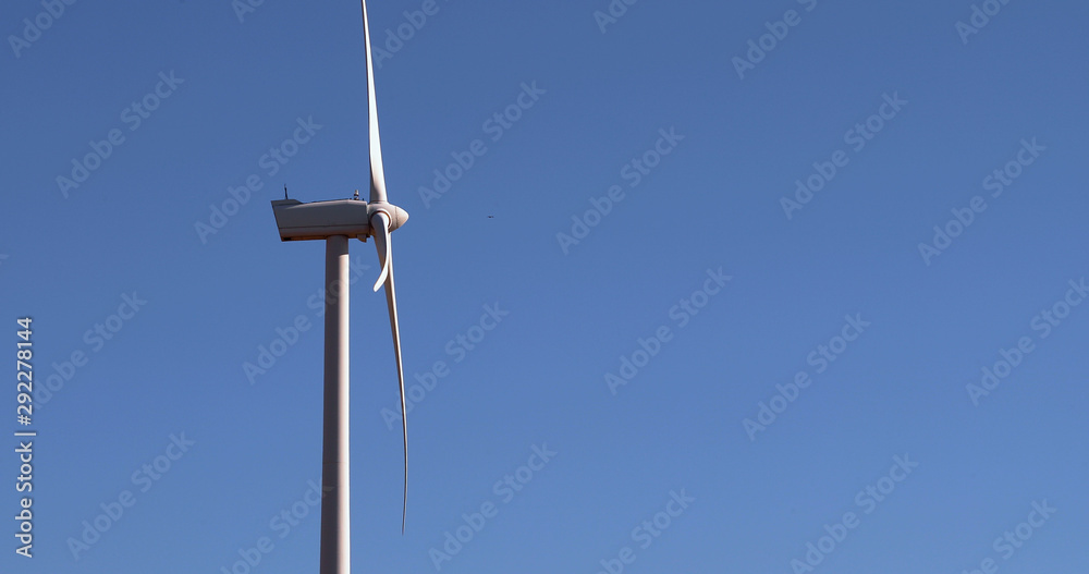 Alternative energy sources. Large blades of wind turbines in rotation with the blue sky in the background - aerial view with a drone - environment & ecological concept Alternative energy sources. Large blades of wind turbines in rotation with the blue sky in the background - aerial view with a drone - environment & ecological concept