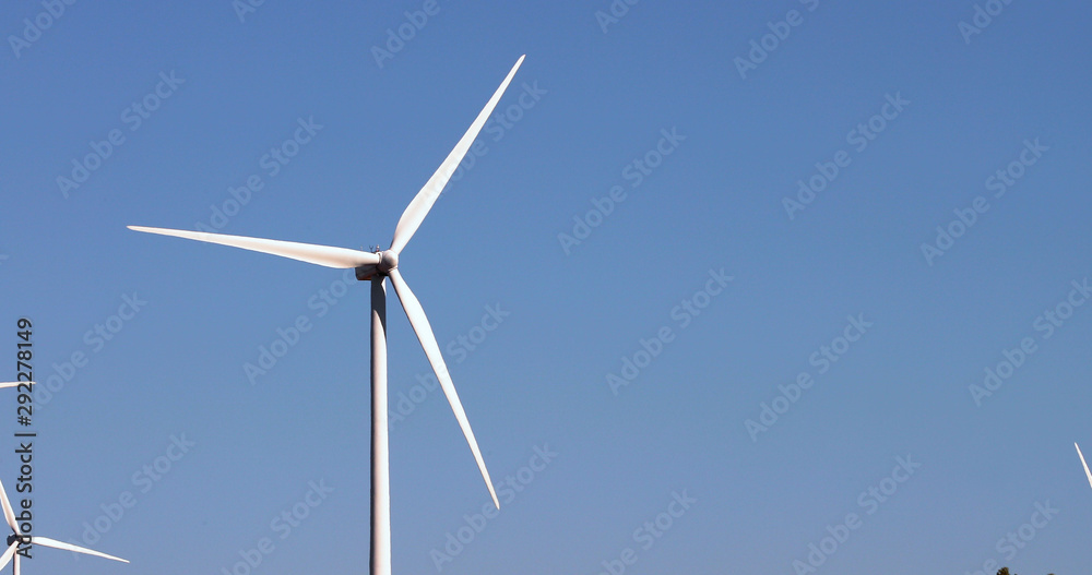 Alternative energy sources. Large blades of wind turbines in rotation with the blue sky in the background - aerial view with a drone - environment & ecological concept