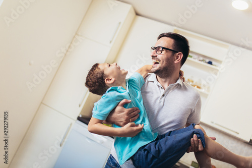 Image of satisfied smiling man piggybacking his son while having fun in modern studio apartment